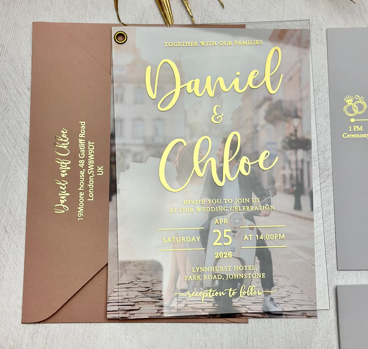 Acrylic wedding invitation with couple photo and eyelet, shown on envelope with personalized foil address