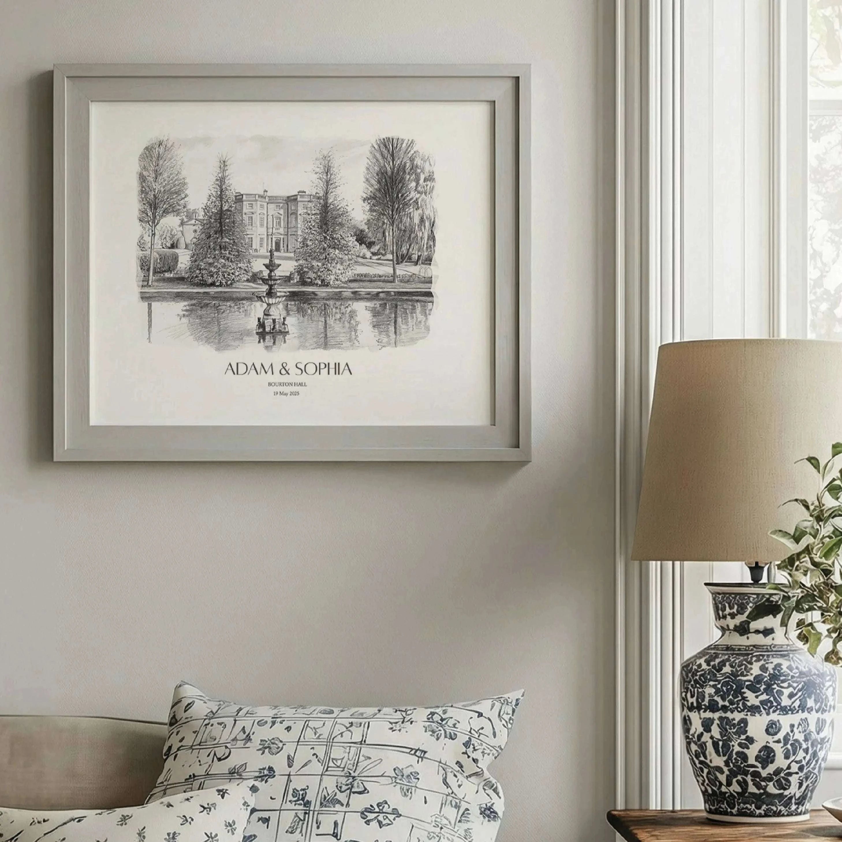 Framed pencil sketch portrait of Bourton Hall displayed in an elegant neutral interior, personalized wedding venue artwork with custom names and date.