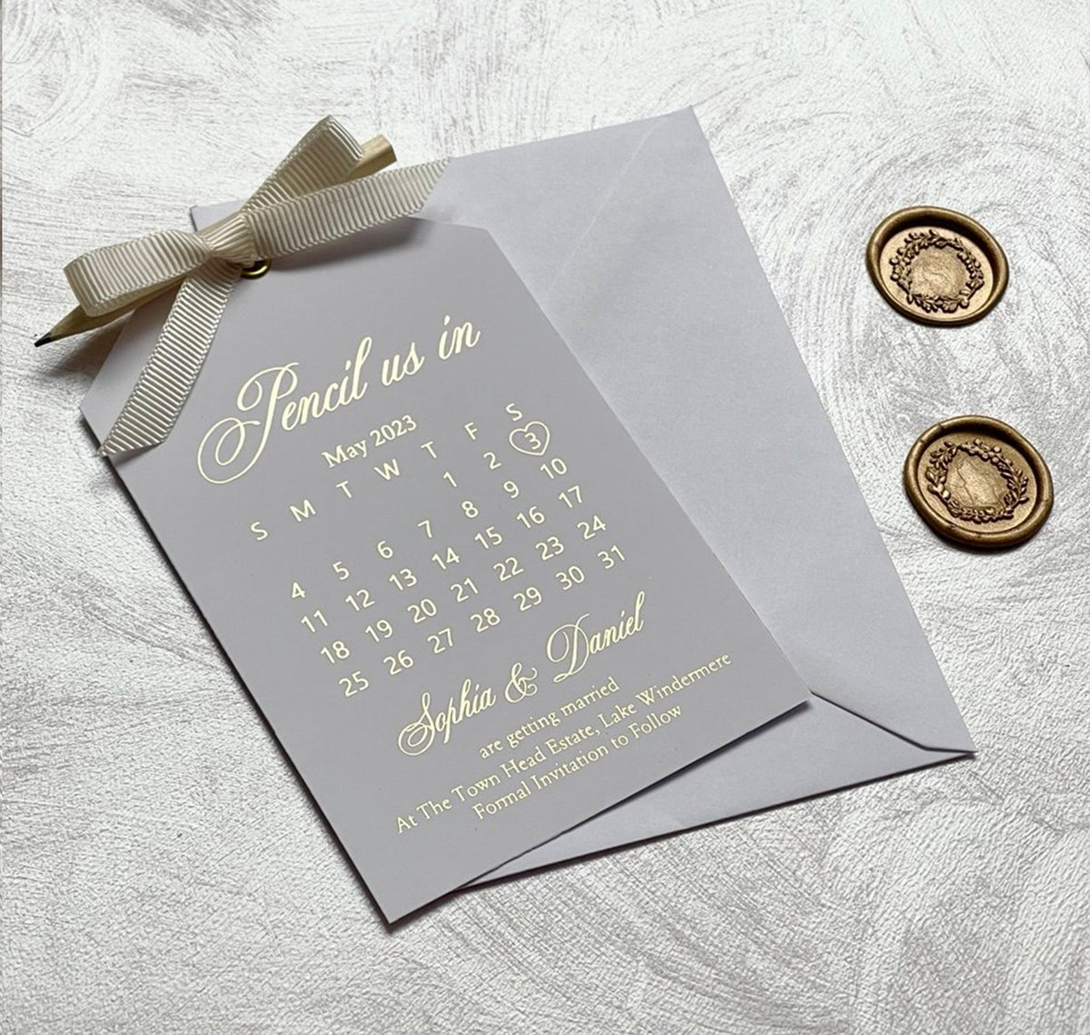 Pencil us in save the date calendar with foil lettering and a pencil, personalized wedding card with the names and date highlighted.