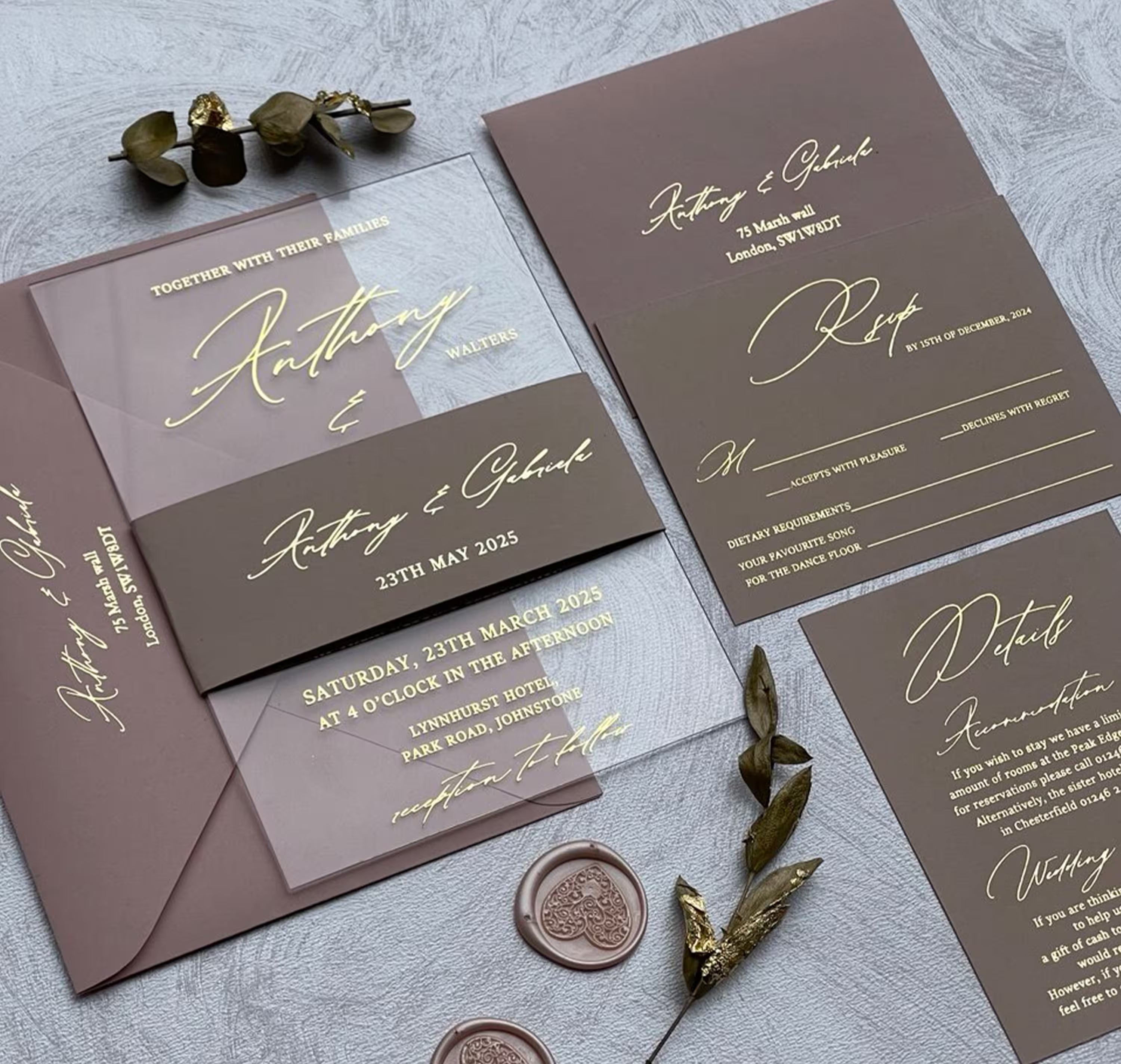 Acrylic wedding invitation with names in gold foil calligraphy, wrapped in a printed belly band with the couple's names and date over a blush envelope