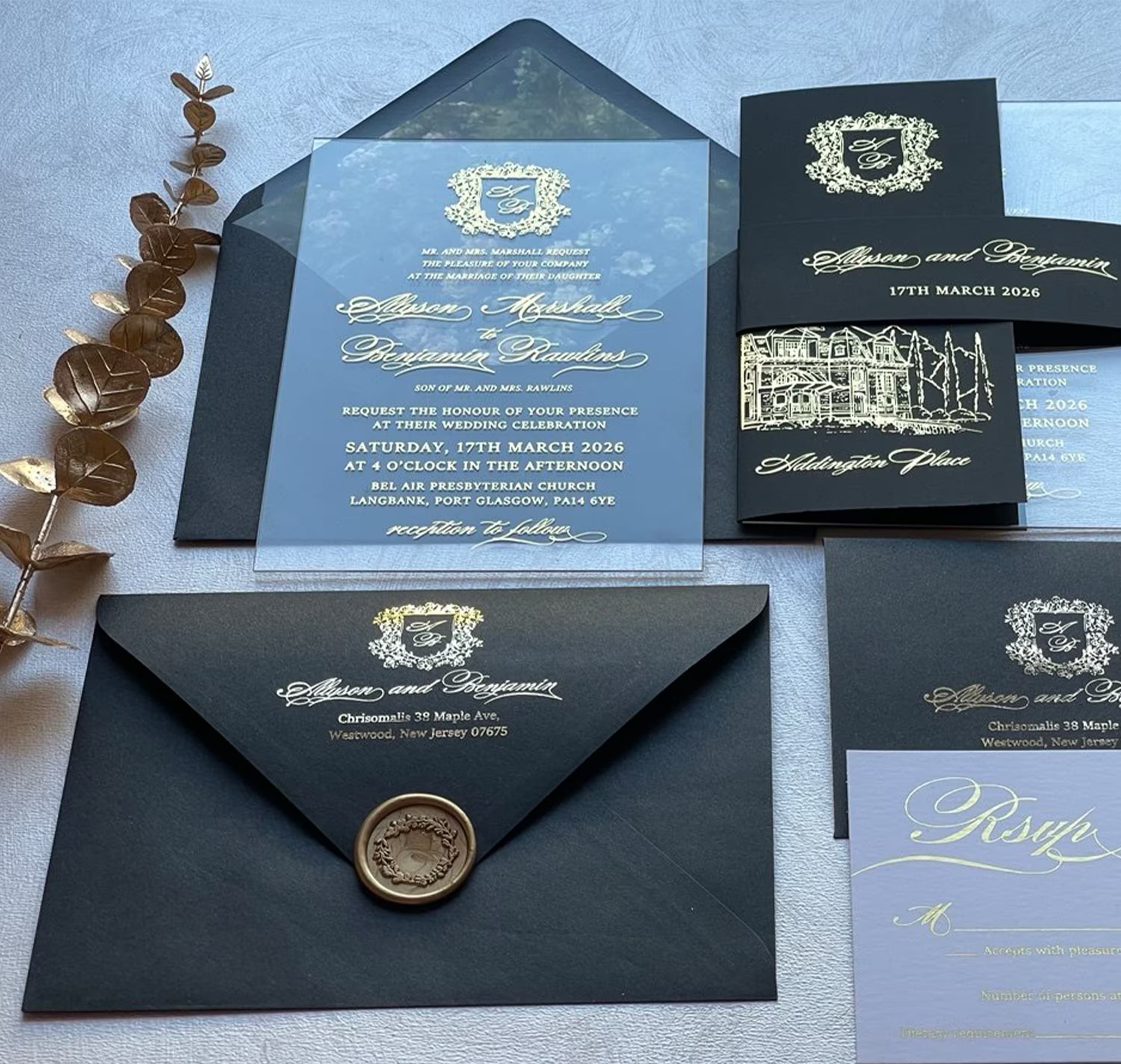 Clear acrylic wedding invitation suite with gold foil monogram crest and venue sketch, shown with a trifold insert, belly band and lined envelope