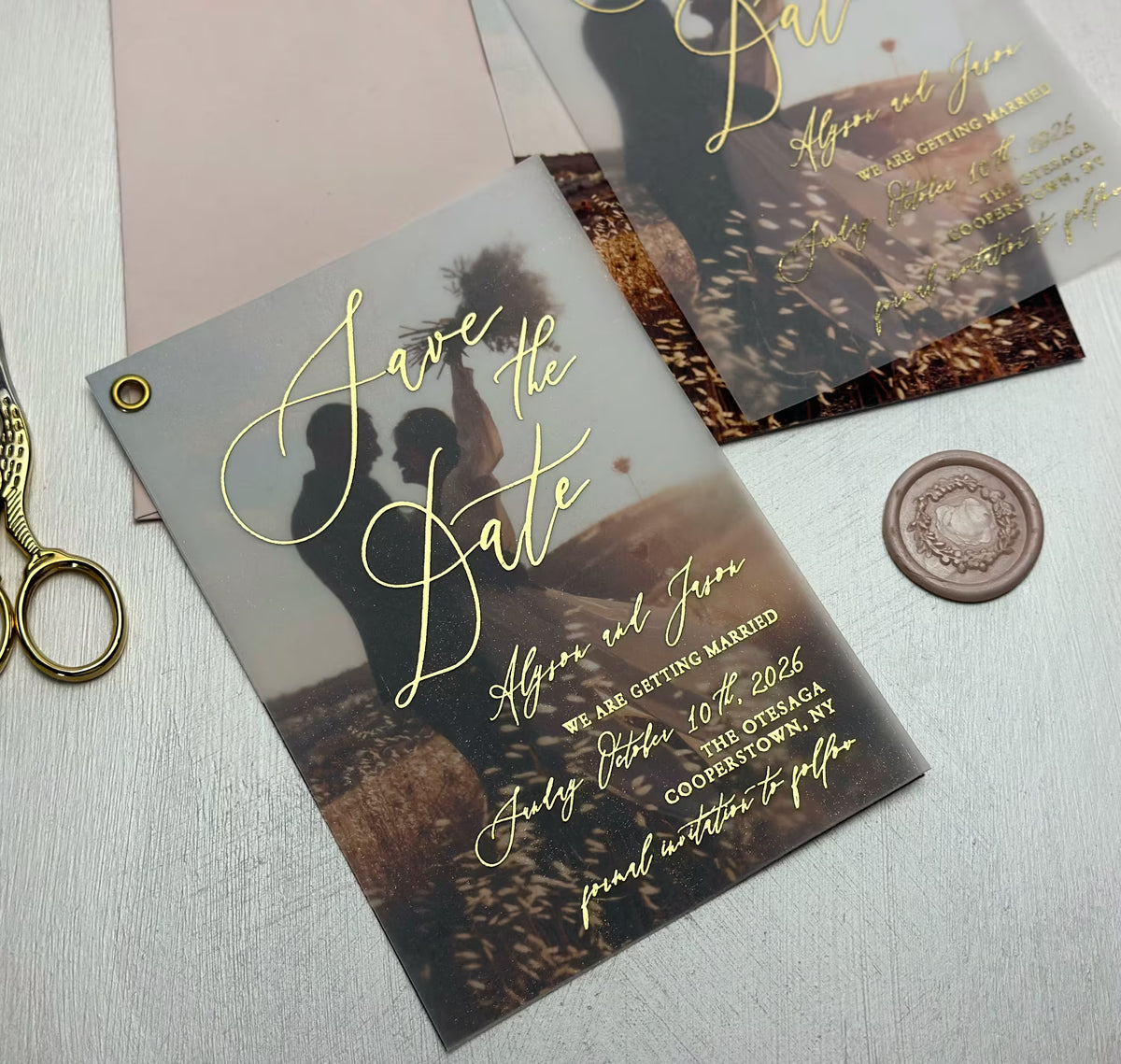 Close up of personalized save the date card with couple photo glowing through vellum and foil lettering
