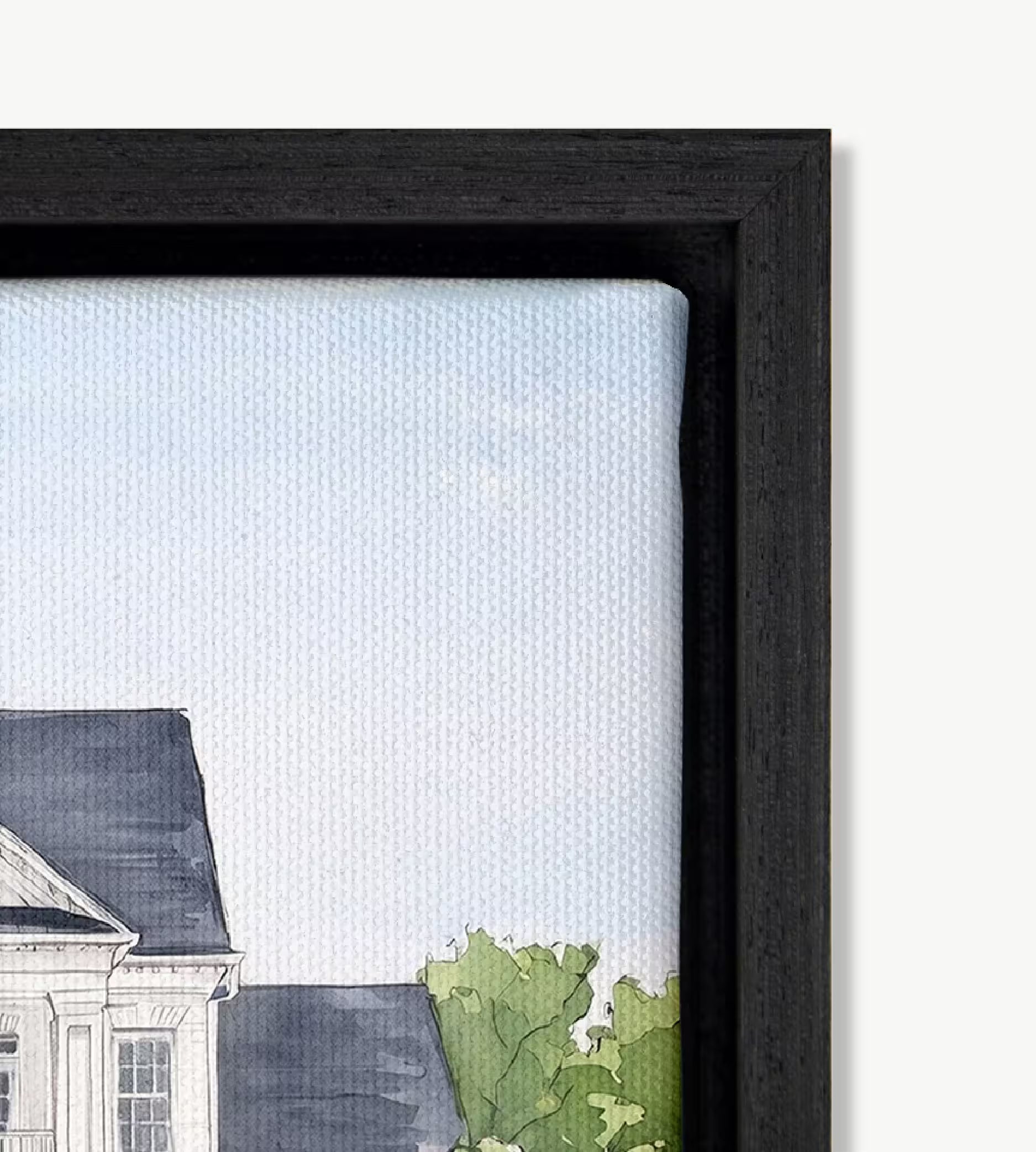 Close-up of a black solid wood floating frame holding a cotton canvas wedding venue portrait, with a soft shadow gap between the canvas and the frame