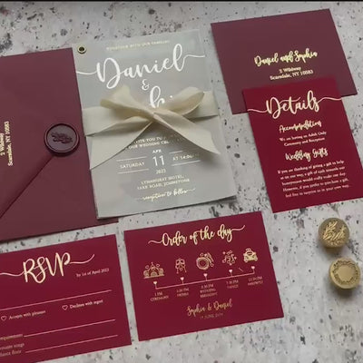 Wedding invitation card with photo and vellum overlay, foil script calligraphy, shown with matching burgundy envelope and details cards flat lay