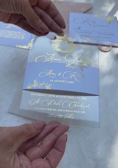 Video of transparent wedding invitations with floral crest monogram in foil on clear acrylic, with optional belly band, envelopes, RSVP card and wax seals