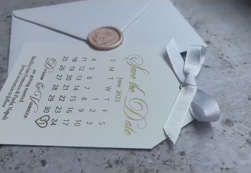 Video of a save the date calendar card with foil lettering and a satin ribbon, personalized wedding save the date tag with an envelope.