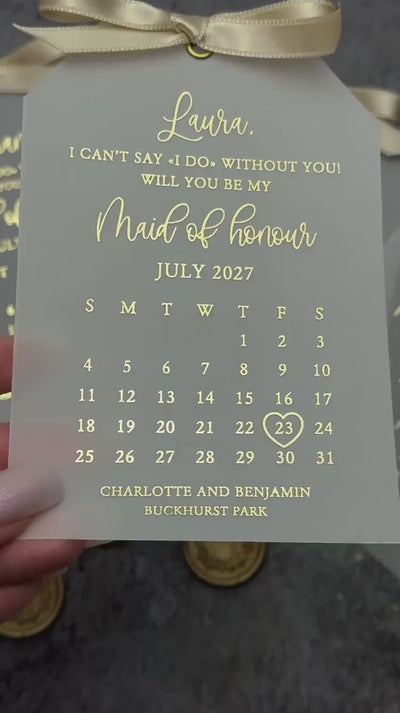 Personalized maid of honor proposal cards on frosted vellum with gold foil script, calendar with heart on the wedding date and gold satin ribbon bows