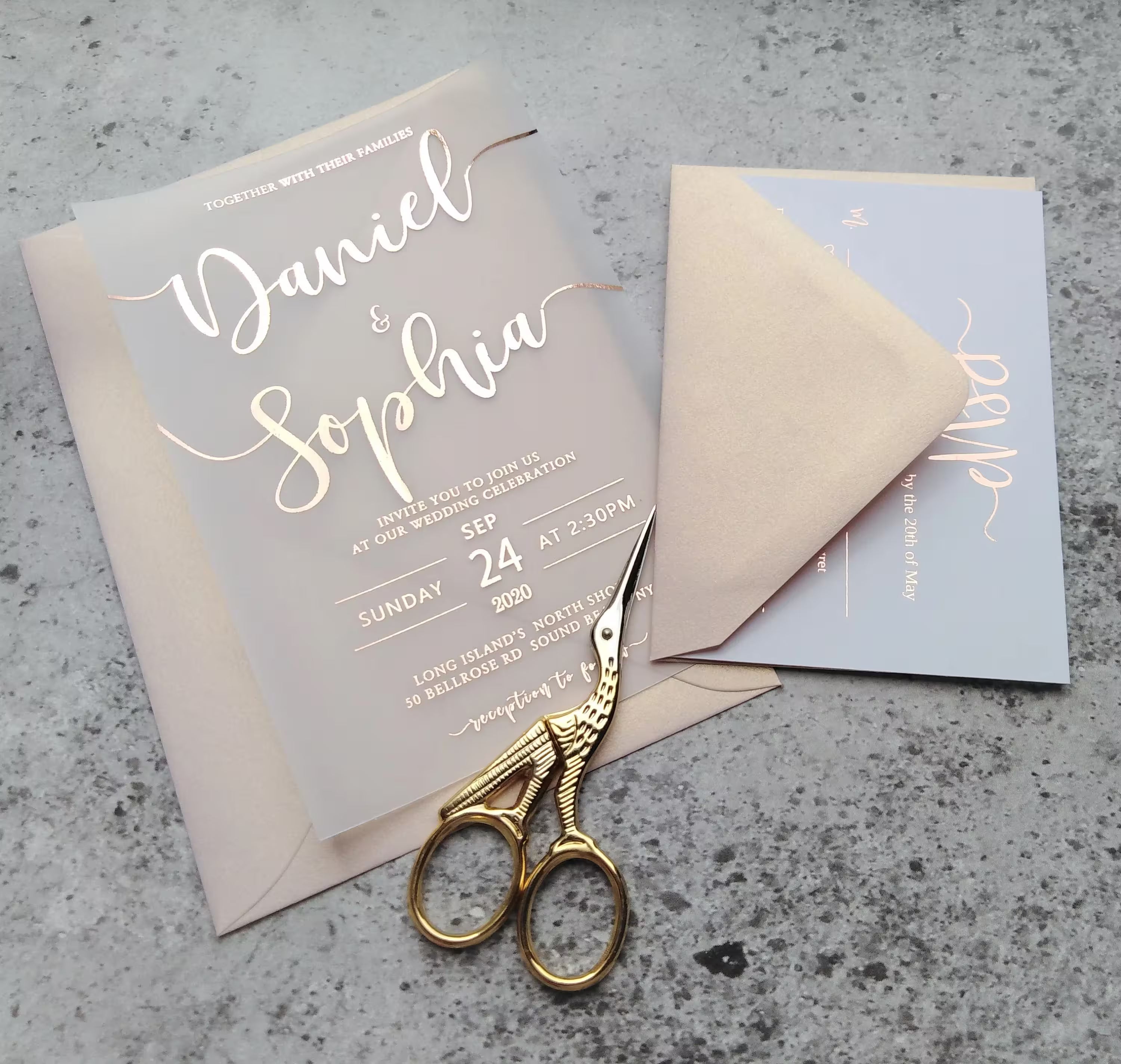 Vellum wedding invitation with rose gold foil calligraphy, blush envelope, and matching RSVP card