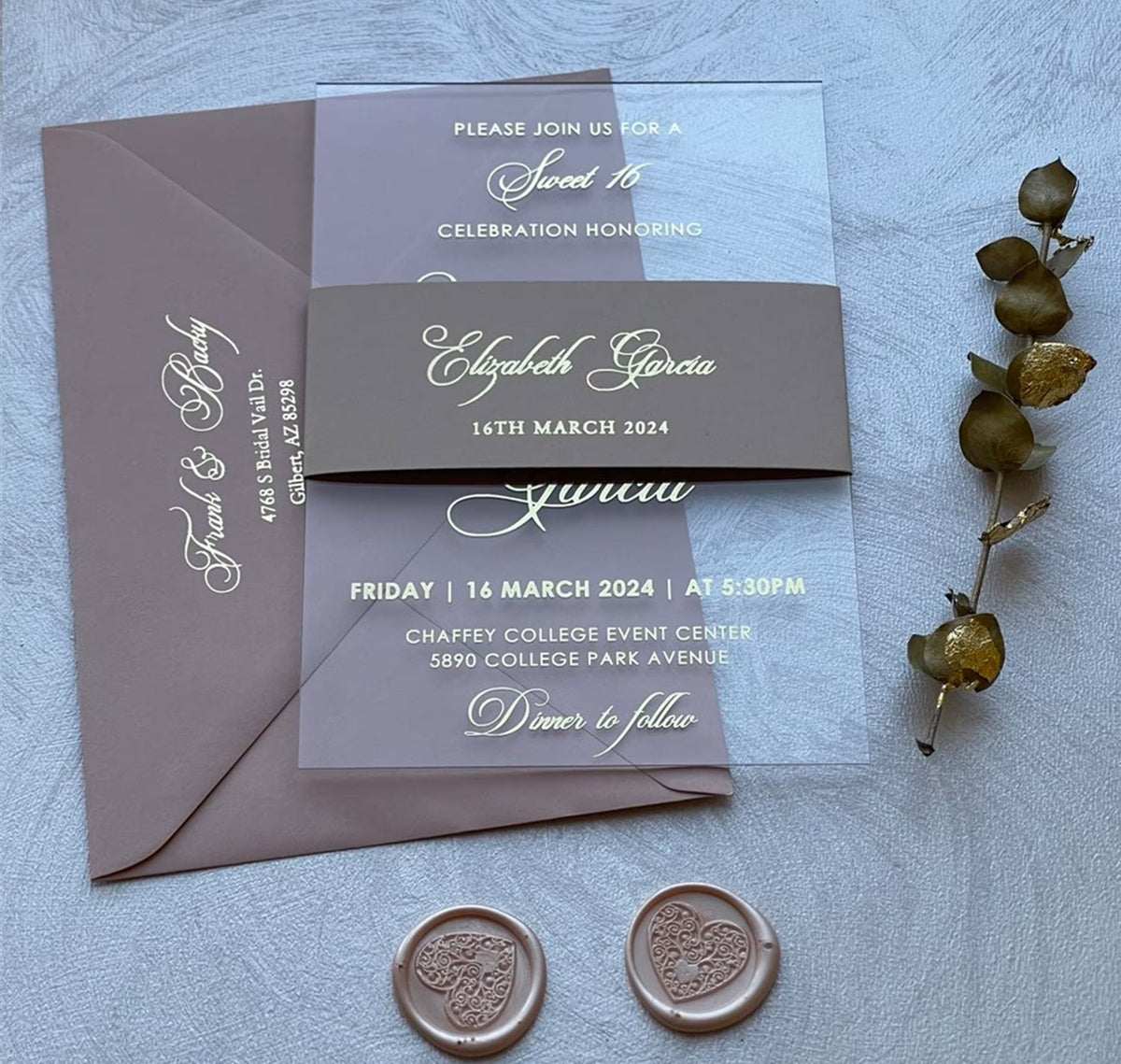 Sweet 16 birthday invitations on clear acrylic with foil lettering and a belly band, personalized with the name, date and venue.